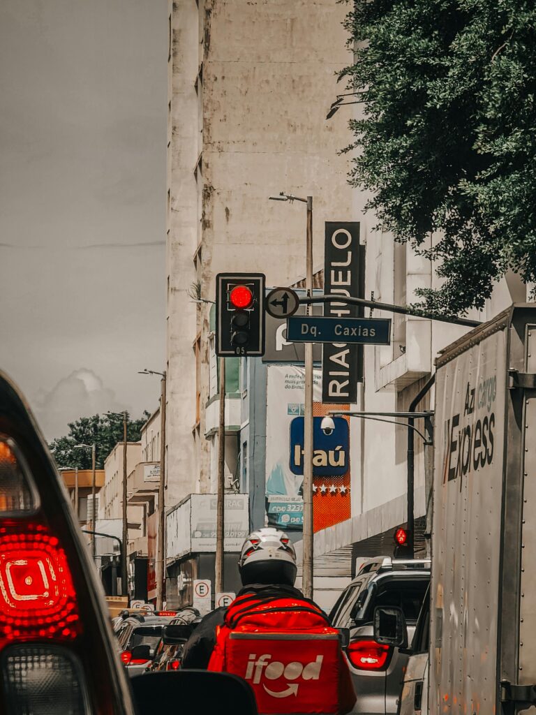 A bustling urban street with traffic and a delivery rider in focus, highlighting modern city life.